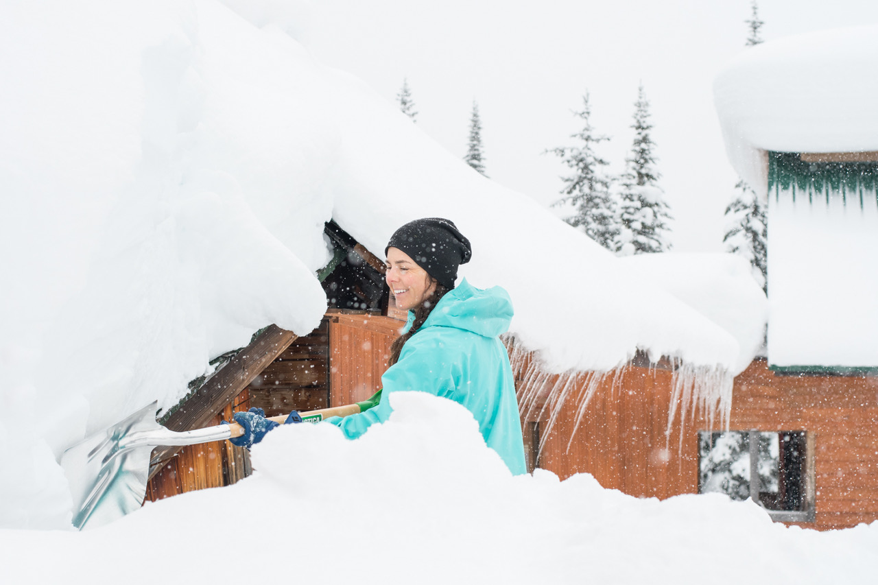 Shovelling snow outside ski lodge.